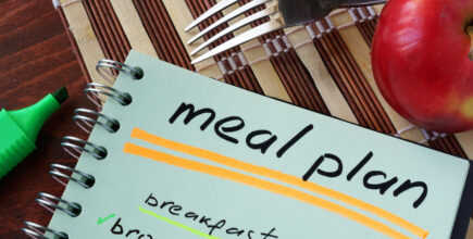 Notepad with meal plan and apple. Diet planning.