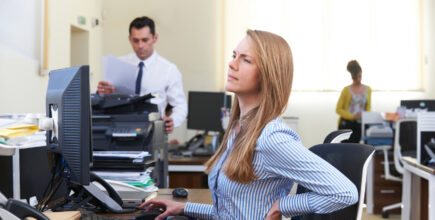 Businesswoman Working At Desk Suffering From Backache